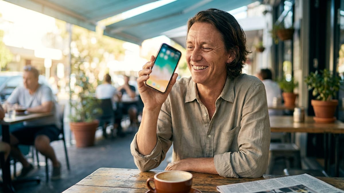 A person smiling at a helpful reply on their phone at a cafe