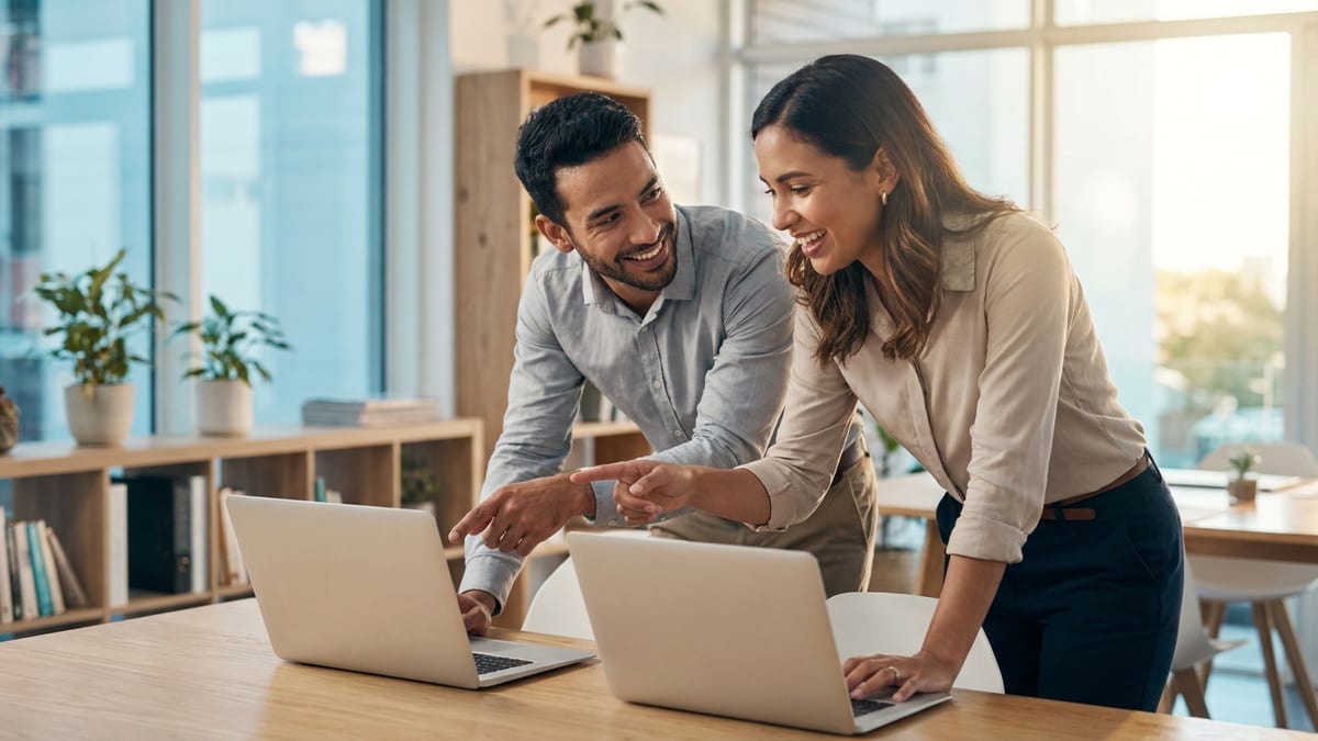 Two sales colleagues collaborating over laptops